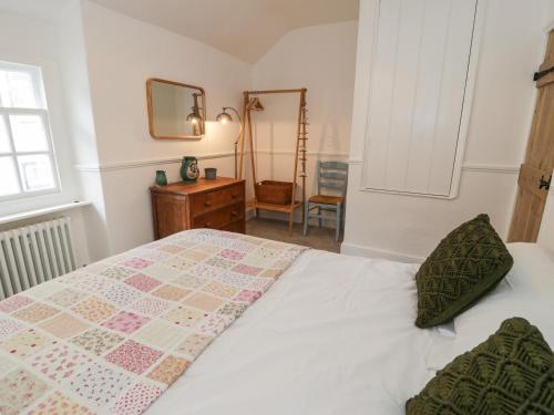 a bedroom with a bed with a quilt on it at Merywen Cottage in Conwy