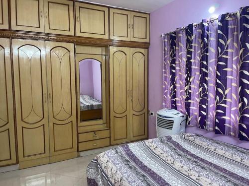 Schlafzimmer mit einem Bett, Holzschränken und einem Spiegel in der Unterkunft Mangala stay home (Malleshwaram) Ground Floor Apts in Bangalore