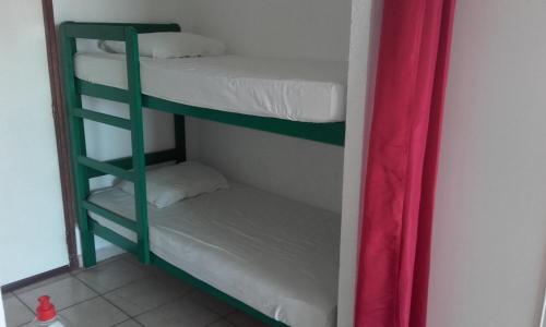 Cette chambre comprend 2 lits superposés et un rideau rouge. dans l'établissement Haute Corse. Studio 4 pers .Plage Piscine. Cervione Prunete ., à Cervione