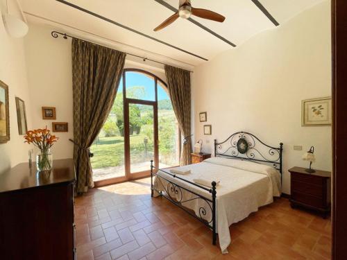 um quarto com uma cama e uma grande janela em Borgo Poggio Bianco em Sarteano