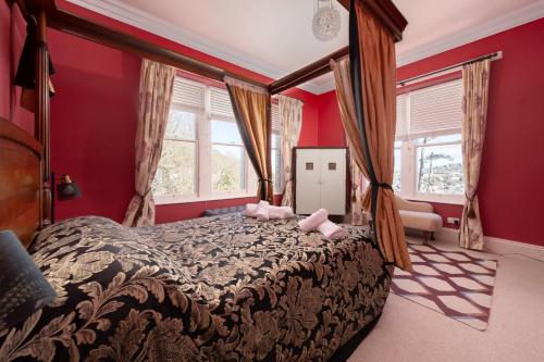 a bedroom with a large bed with red walls at Westwell Hall in Ilfracombe