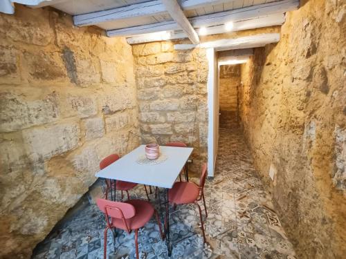 a table and chairs in a room with a wall at Historic Center Apartment in Agrigento