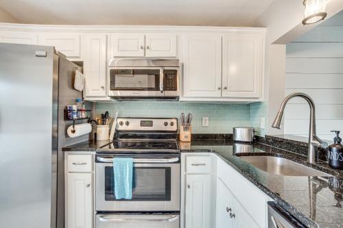 a kitchen with white cabinets and a stove and a sink at Beachfront Condo with 3 Pools on St Helena Island! in Oceanmarsh Subdivision