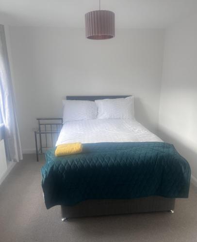 a bedroom with a bed with a green blanket at Market Harborough Guest House in Lubenham