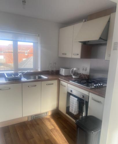 a kitchen with white cabinets and a sink and a window at Market Harborough Guest House in Lubenham