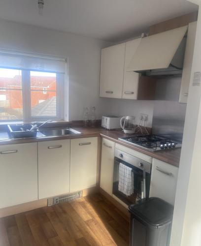 a kitchen with white cabinets and a sink and a window at Market Harbour Guest House in Lubenham