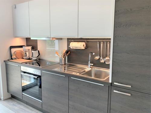una cucina con armadi bianchi e un lavandino in acciaio inossidabile di Die"53er" - Fit und Vital - a90094 a Grömitz