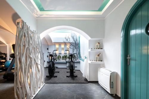 a gym with exercise equipment in a room with a ceiling at Santorini Miracles Suites in Perissa