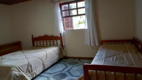 sypialnia z 2 łóżkami i oknem w obiekcie Casa boa vista w mieście Campos do Jordão