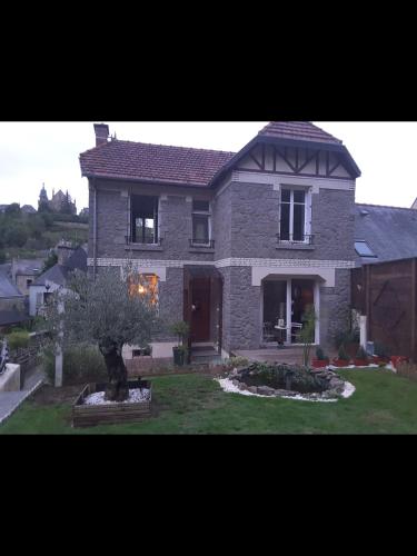 une grande maison en briques avec un arbre dans la cour dans l'établissement Maison papillon, à Fougères