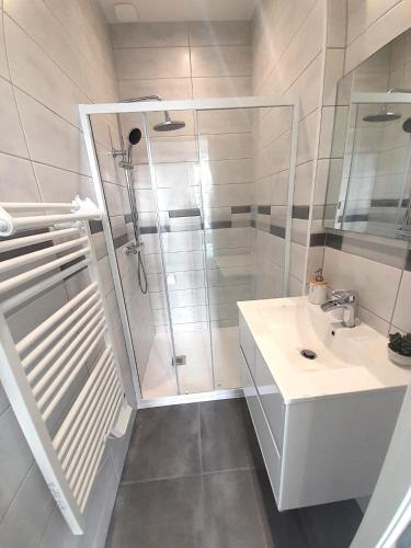 une salle de bain blanche avec une douche et un lavabo dans l'établissement le bugatti T2 en face de la gare, à Châteauroux