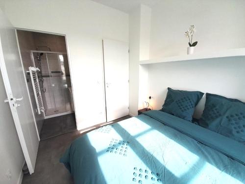 - une chambre avec un lit doté de draps bleus et une douche dans l'établissement le bugatti T2 en face de la gare, à Châteauroux