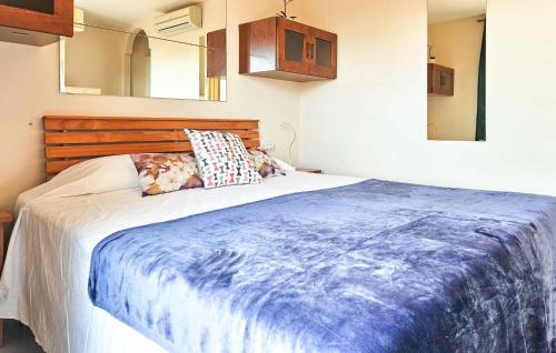 a bedroom with a bed with a blue blanket on it at Nice Apartment In La Cala De Mijas With Wifi, Outdoor Swimming Pool And Swimming Pool in La Cala de Mijas