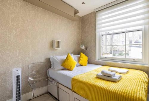 a bedroom with a bed with yellow sheets and a window at Modern design 3BRs 2F house close to Victoria in London