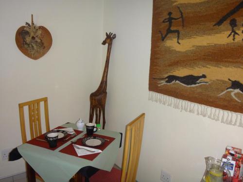 a dining table with a giraffe on the wall at Maison Ambre Guesthouse in Windhoek