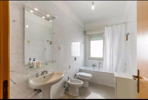 bagno bianco con lavandino e servizi igienici di SicilyRooms a Vittoria