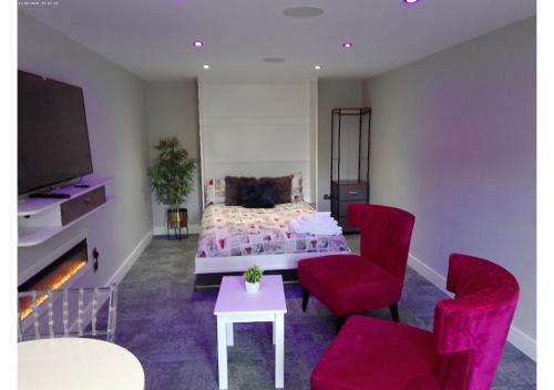 a bedroom with a bed and two red chairs at Cosy Studio in Milton Keynes