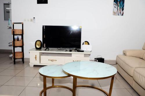 a living room with a table and a tv at Home By Dina'Sty in Yaoundé