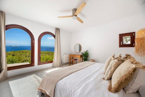 a white bedroom with a large bed and large windows at Sea La Vie - Stunning Sea and Jungle Views in San Antonio