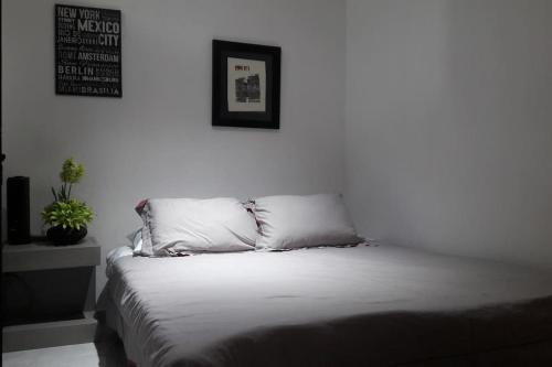a white bed with two pillows in a bedroom at Departamento cerca plaza del sol - Expo Guadalajara in Guadalajara