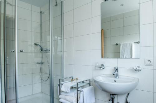 a white bathroom with a sink and a shower at Gästehaus Brugger in Bregenz