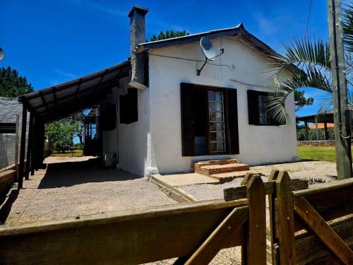 ein kleines weißes Haus mit einem Holzzaun in der Unterkunft Casa de playa in Santa Vitória do Palmar