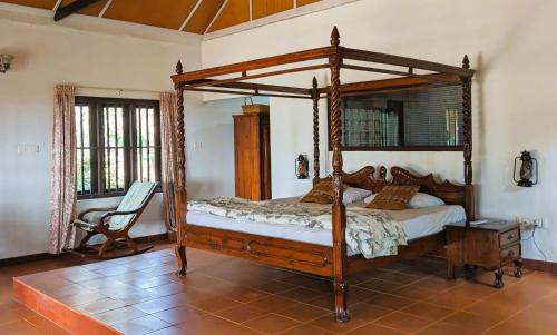 una camera con letto a baldacchino e sedia di Baycliff Cottages a Varkala