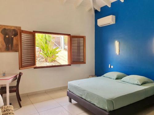 Dormitorio azul con cama y ventana en Villa Horizon à Marie-Galante en Grand-Bourg