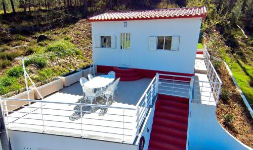 a house with a deck with a table and a chair at Cantinho do Vale - Oleiros in Oleiros