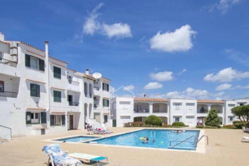 a swimming pool in front of a building at Apartamento en Cala en Porter, Menorca. in Cala'n Porter