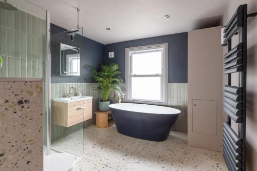 a bathroom with a tub and a plant in it at Stylish Victorian 2 Bed Terraced House with Garden in Cambridge