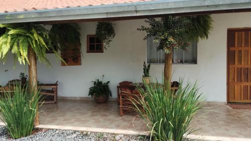 une maison blanche avec des plantes et une terrasse dans l'établissement Casa flores do campo, à Campos do Jordão