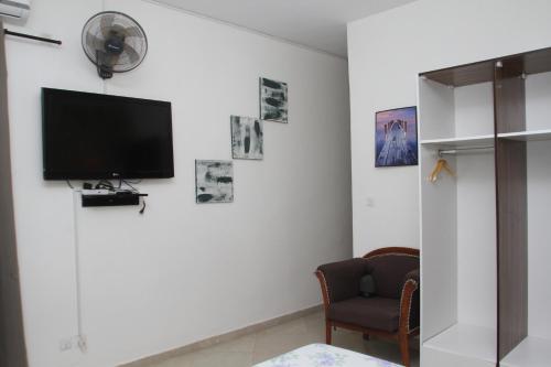 a living room with a tv on a white wall at "La Coquille", joli loft, moderne, propre, sûr et calme au cœur de Saly in Saly Portudal