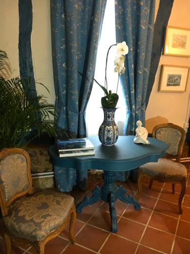 a blue table with a vase with flowers on it at Le Logis Fleurs et jardins de Pitry in Thierville