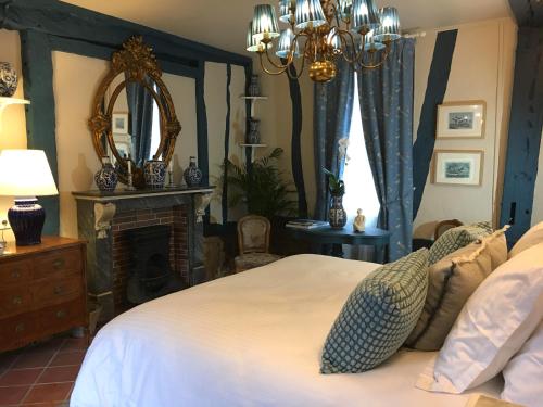 Schlafzimmer mit einem Bett, einem Kamin und einem Spiegel in der Unterkunft Le Logis Fleurs et jardins de Pitry 