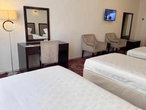 a hotel room with two beds and a desk and chairs at فندق أبراج الريان المكية Al Rayyan Makiya Towers Hotel 1 in Makkah