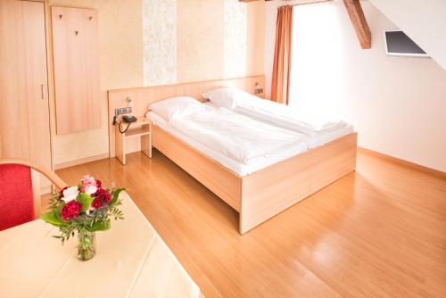a bedroom with a bed and a table with a vase of flowers at Gasthof zum Lamm in Gomadingen