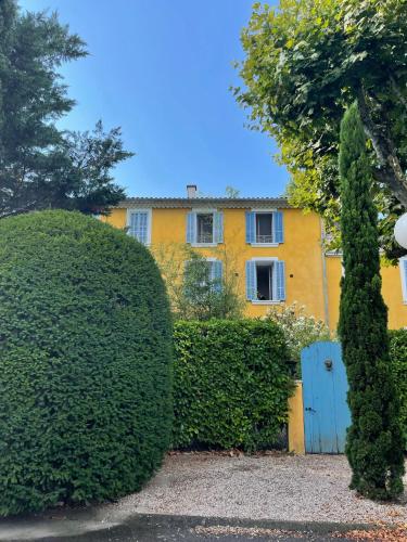 une maison jaune avec une haie et une porte bleue dans l'établissement LA BASTIDE D'AIX, à Aix-en-Provence