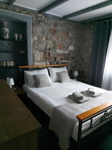 una camera da letto con un grande letto bianco e un muro in pietra di Apartment Balinovaca a Skradin