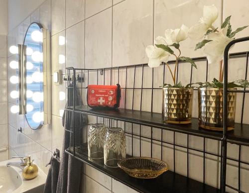 - une salle de bains pourvue d'une étagère avec des fleurs et des verres dans l'établissement NEU! Art Deco Design-Luxus-Apartment, am Markt, Garten, à Gera