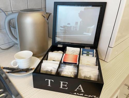 a box of tea sitting on a desk with a cup at Art Deco Design Apartment, 65 Zoll TV, Waschtrockner, beste Lage, am Markt in Gera