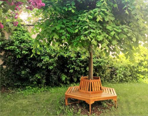 a wooden bench with a tree sitting in the grass at Art Deco Design Apartment, 65 Zoll TV, Waschtrockner, beste Lage, am Markt in Gera