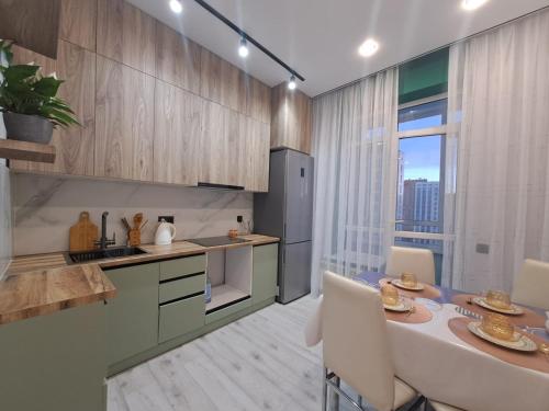 INJU Arena 1-rooms apartments في أستانا: مطبخ مع طاولة وبعض الكراسي في الغرفة