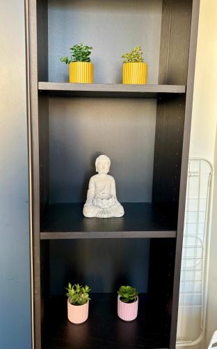 a shelf with potted plants and a statue on it at Le Secret de l'Architecte : proche Centre et Gare in Dijon