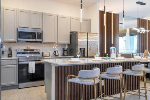 une cuisine avec des placards blancs et un îlot avec des tabourets de bar dans l'établissement 6163 Fantastic Home with 12BD, à Orlando