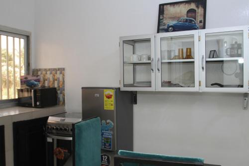 a kitchen with white cabinets and a refrigerator at " Le Nid Douillet ", un fabuleux studio, calme, cosy et bien climatisé au centre de saly in Saly Portudal