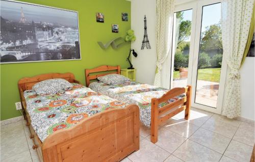 two beds in a bedroom with a green wall at Gorgeous Home In Eyguieres With Outdoor Swimming Pool in Eyguières