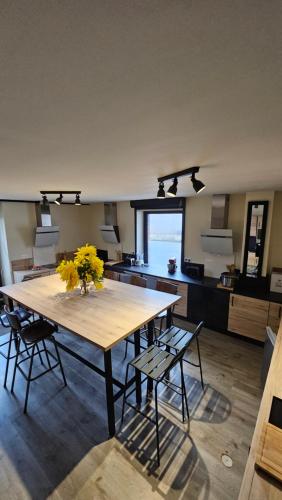 une cuisine avec une grande table en bois ornée de fleurs jaunes. dans l'établissement Coliv'Castres, à Burlats
