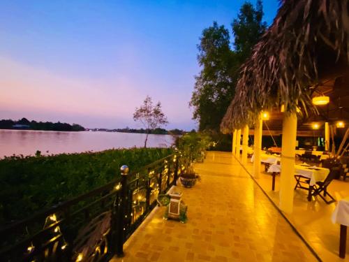 een patio met uitzicht op het water in de nacht bij Mango Home Riverside in Ben Tre