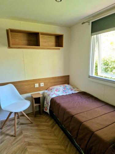 une chambre avec un lit, une chaise et une fenêtre dans l'établissement Mobilhome N°222 : 3ch / 2sdb dans camping 4*, à Gastes